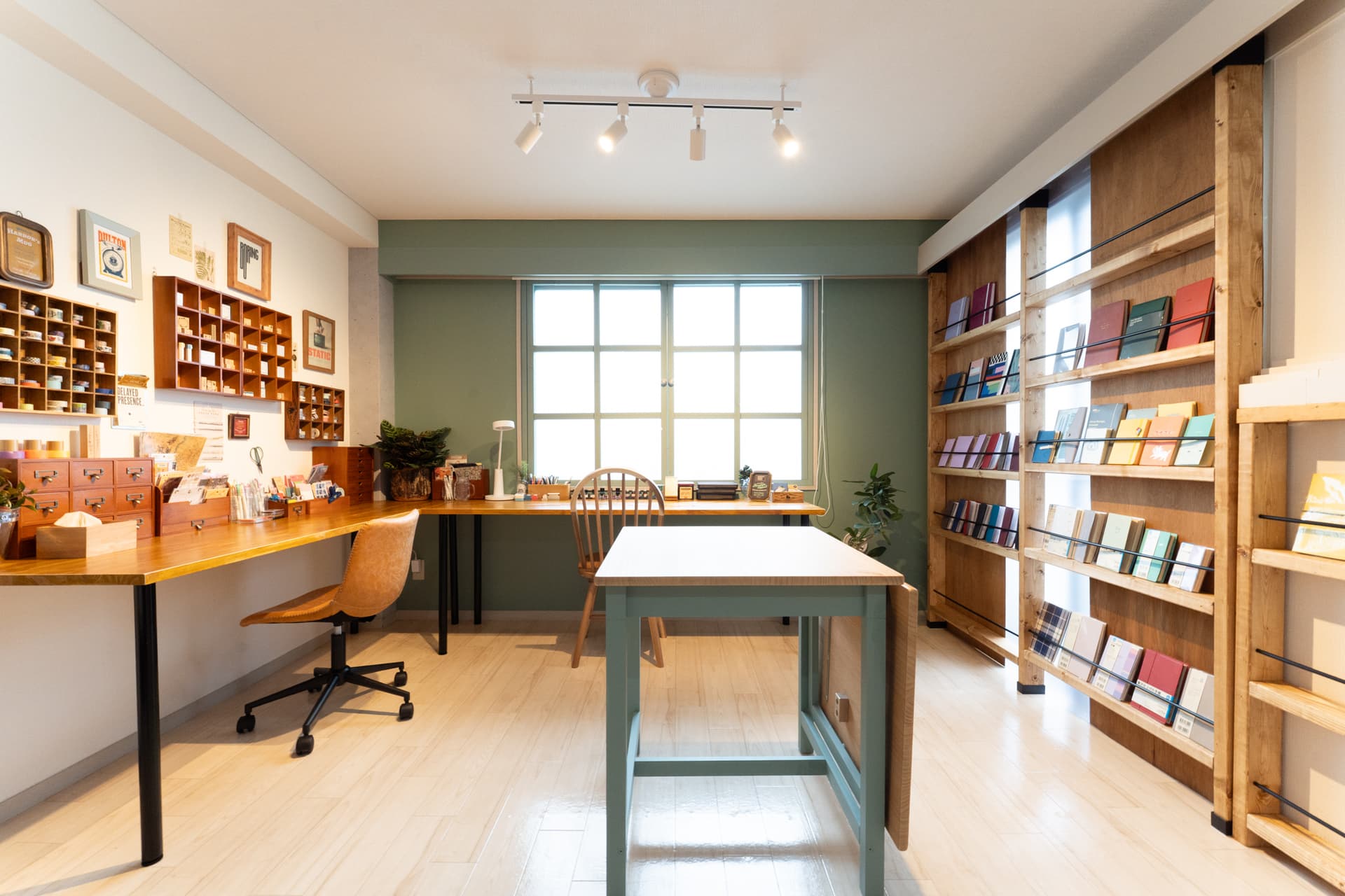 Interior view of a bright stationery shop featuring wooden display shelves, a large desk, and organized product displays.
