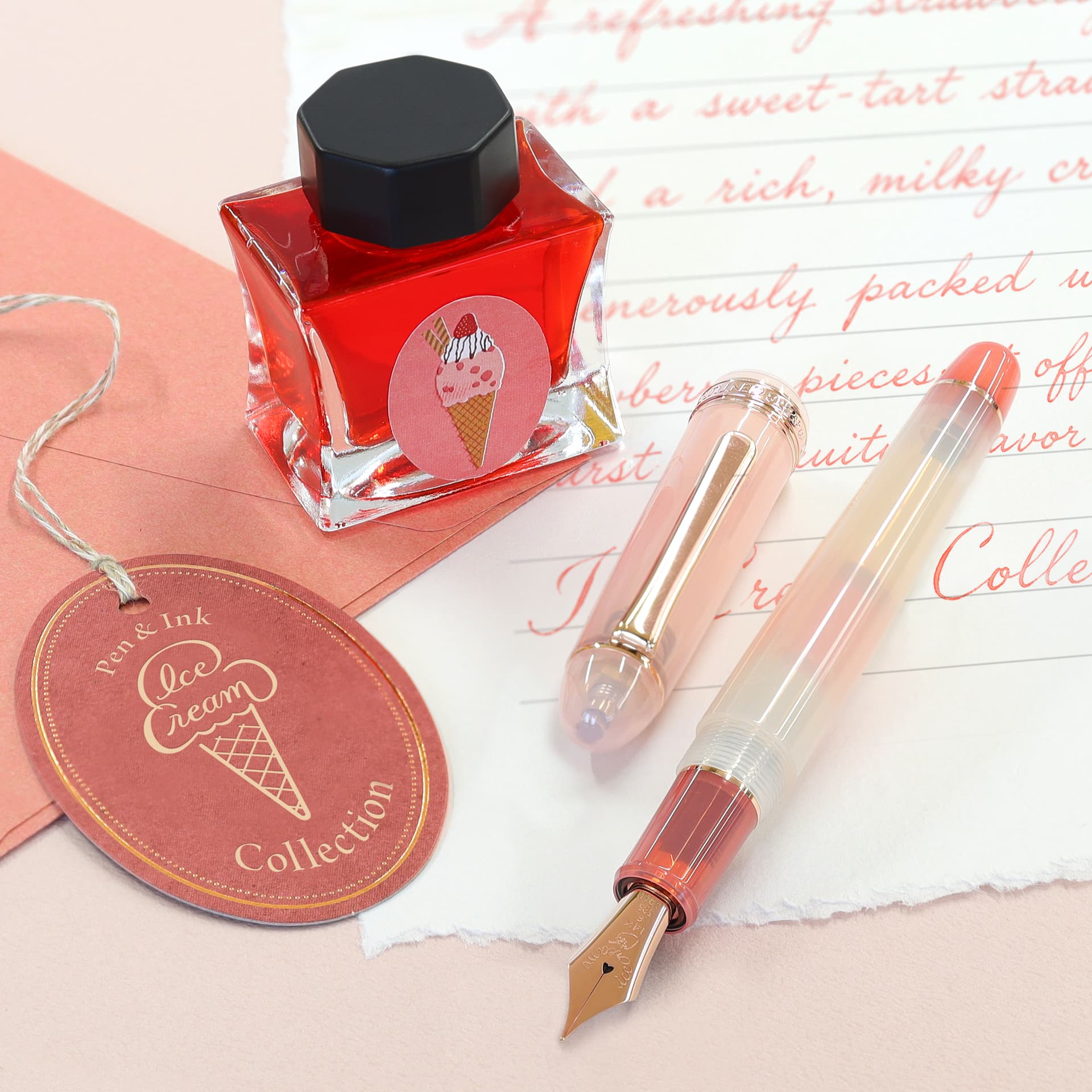 Red bottled ink and a translucent marbled fountain pen resting on handwritten pink stationery with an ice cream tag.