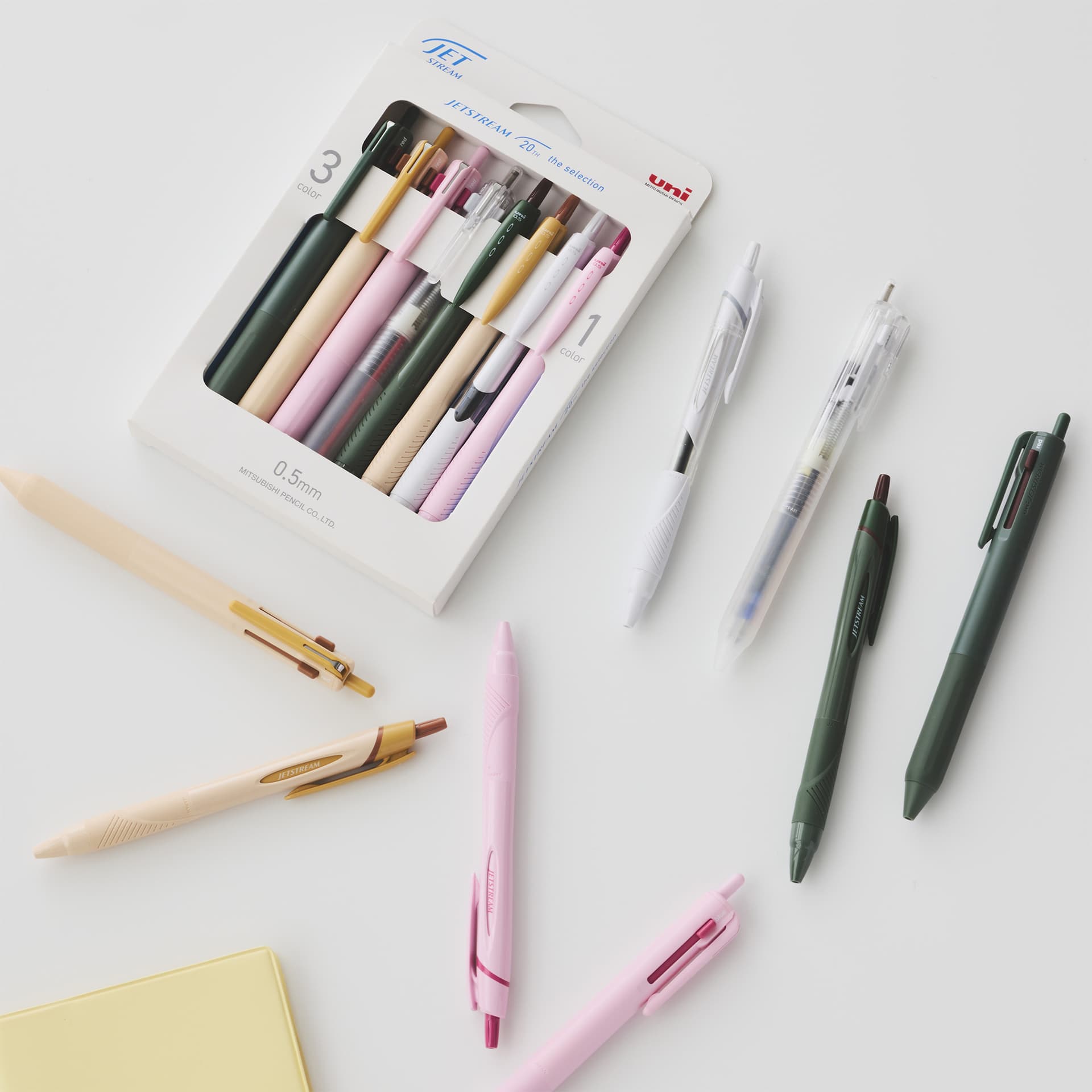 Mitsubishi Uni Jetstream ballpoint pens in various colors arranged next to their original product packaging.