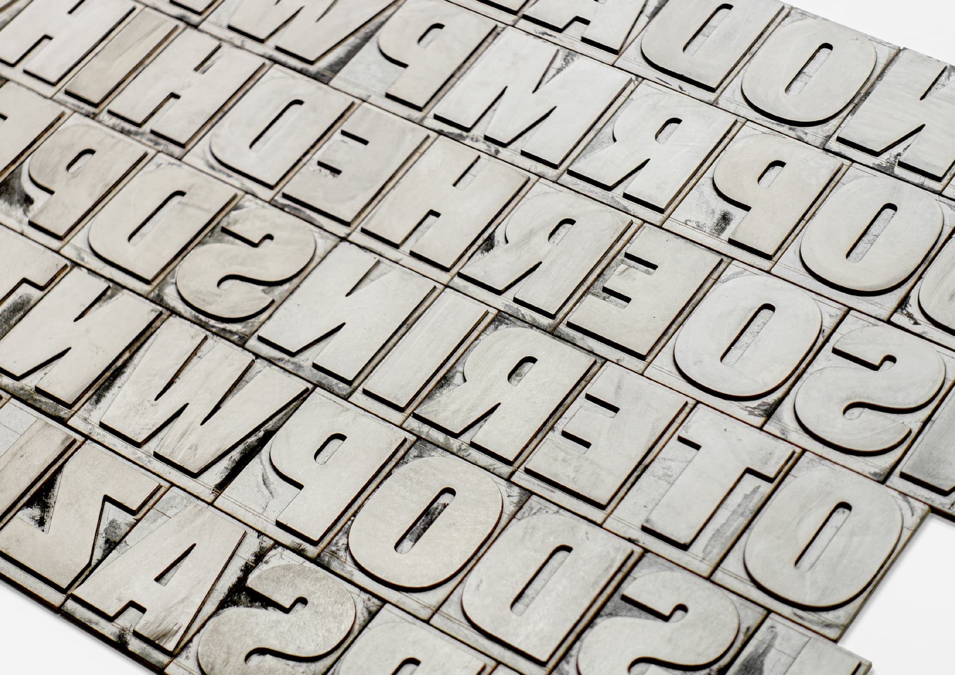 Various silver metallic alphabet letters arranged in neat rows on a white surface.
