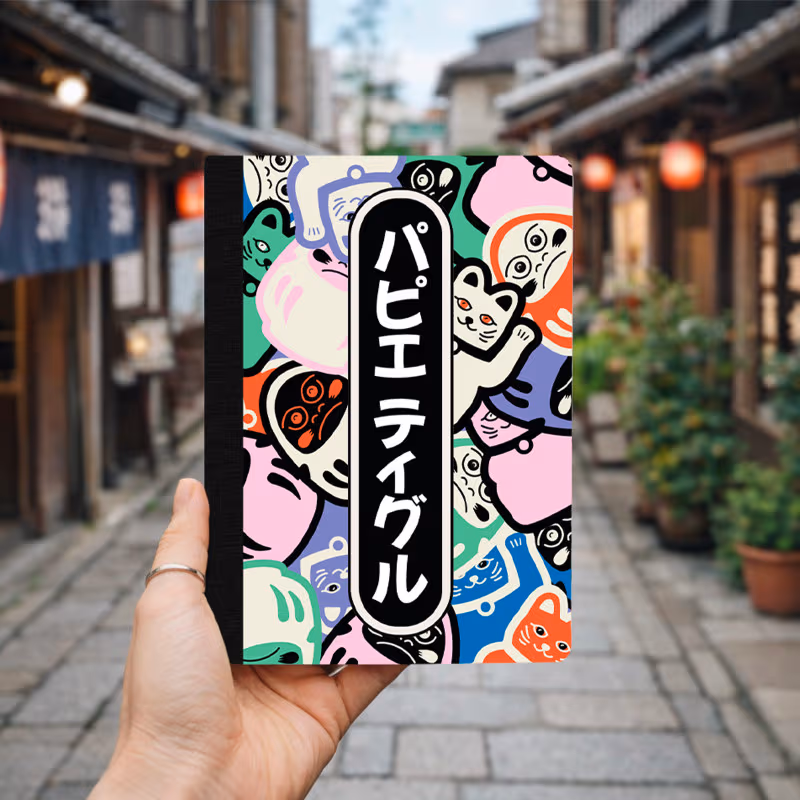 A colorful notebook featuring a playful pattern of various cartoon animal faces with a vertical black text label.